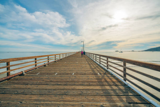 Wide long wooden pier on the beach with beautiful cloudy sky on background, California coastline stock photo