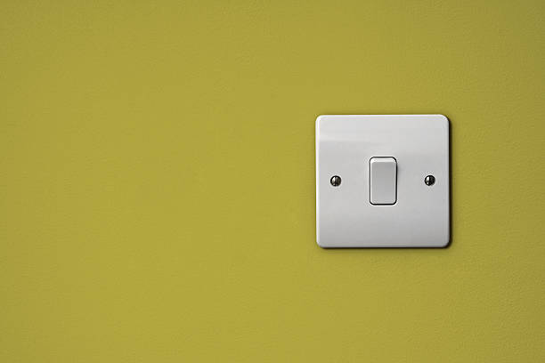 Wide plate white light switch on a chartreuse wall Light switch on wall light switch stock pictures, royalty-free photos & images