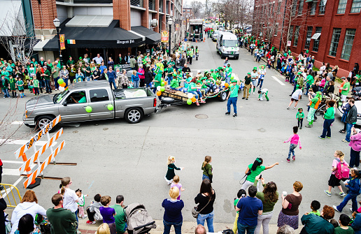 Little Rock, Arkansas, USA - March 15, 2014: A wide view of the people watching a St. Patrick's day parade.Crowds of spectators of all ages line the street on both sides to watch.