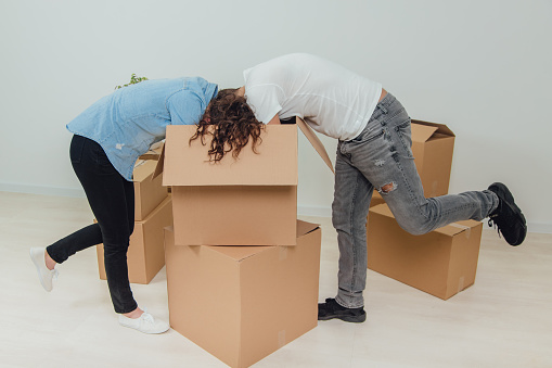Wife And Husband Are Busy Unpacking The Carton Boxes They Are Standing ... Wife And Husband Are Busy Unpacking The Carton Boxes They Are Standing ...