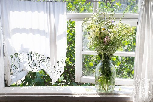 Bouquet of wild flowers on windowsill. Window of house in countryside