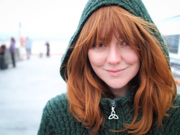 Wild Irish Rose A portrait of a beautiful red headed woman in an emerald wool hood smiling at the camera. irish women stock pictures, royalty-free photos & images