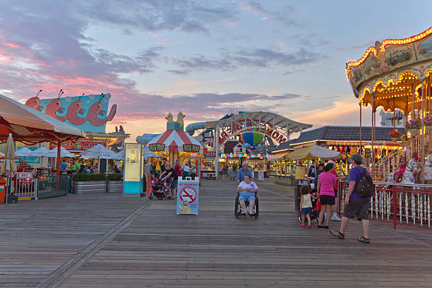 Wildwood Boardwalk at Twilight Wildwood, New Jersey, USA - September 5, 2014:  Crowd of tourists enjoy the popular Wildwood boardwalk that is full of rides, shopping and other entertainment at sunset on September 5, 2014 in Wildwood, New Jersey boardwalk stock pictures, royalty-free photos & images