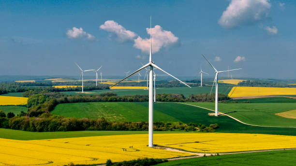 Wind farm in France French landscape with a wind farm above rapeseed fields and forests under an azure blue sky dotted with a few small white clouds. vertical axis wind turbine stock pictures, royalty-free photos & images