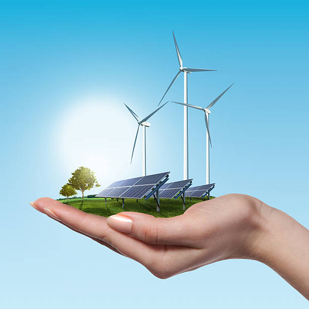 Wind turbines and solar panels in female hand stock photo