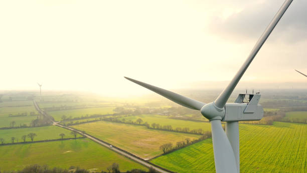 windkraftanlagen auf einem feld bei sonnenuntergang - windenergie stock-fotos und bilder