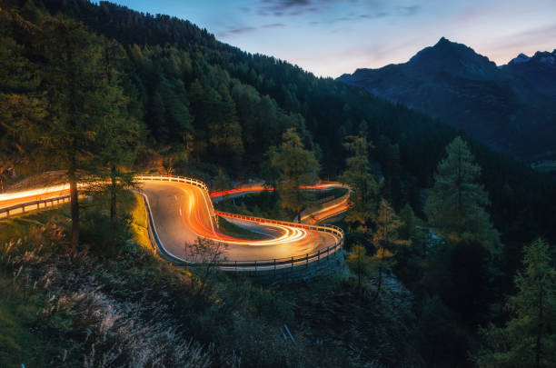 Winding road of Maloja Pass in Switzerland The winding mountain road with light tracks from cars at the evening, Maloja Pass, Switzerland long exposure stock pictures, royalty-free photos & images