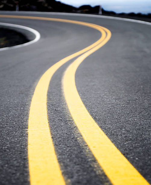 Winding Yellow Road Line A double yellow line on a road curving into the distance. dividing line road marking photos stock pictures, royalty-free photos & images