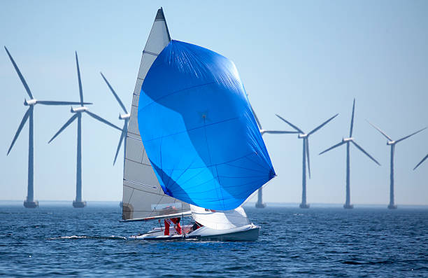Windmills and a sailboat in the middle of the sea stock photo