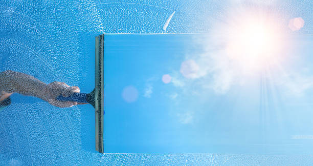 window cleaner cleaning window with squeegee and wiper on a sunny day stock photo