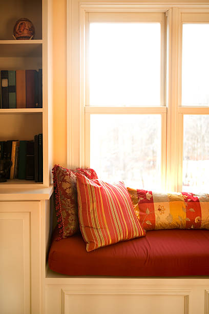 window seat A view of a window seat with the sunlight streaming in the window. alcove window seat stock pictures, royalty-free photos & images