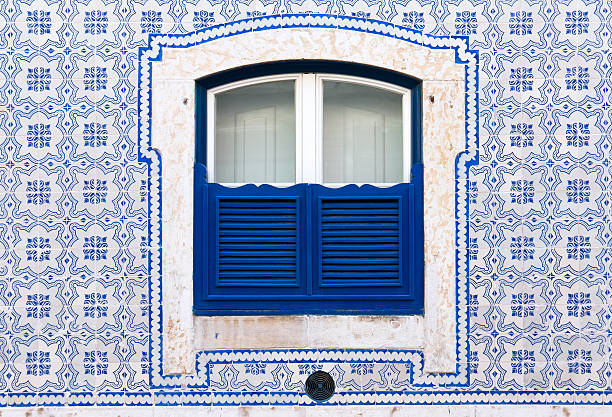 Window with beautiful blue tiles "Typical window with beautiful tiles and blue wooden closed shutters. Was seen in the City of Lisbon. These tiles are named in Portugal Azulejo. Azulejo is a form of Portuguese or Spanish painted, tin-glazed, ceramic tilework.For more pictures, please look here:" portuguese culture stock pictures, royalty-free photos & images