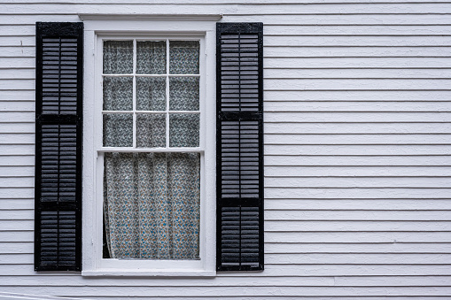 window with open shutters of an white colored wooden house
