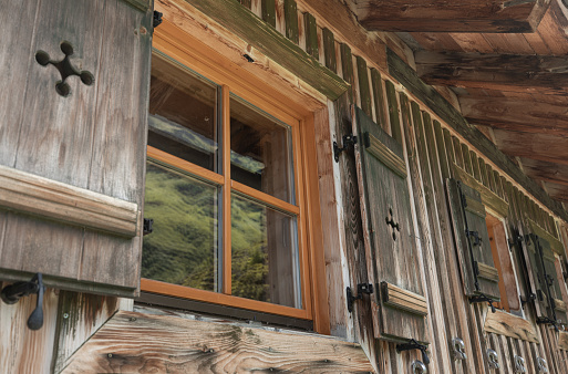 windows and shutters of a cozy Austrian village house, wooden wall, reflection in the window. High quality photo