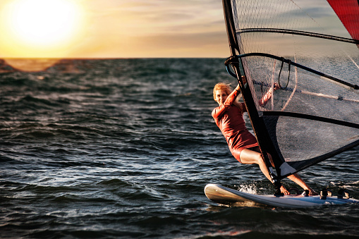 Windsurfer Surfing The Wind On Waves In Neusiedl Lake in Austria at Sunset. Recreational Water Sport. Summer Fun Adventure Activity.
