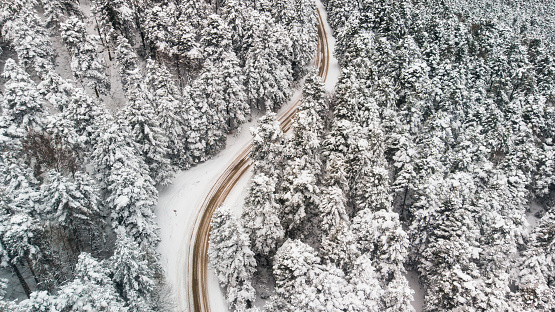 windy road in snow covered forest, top down aerial view