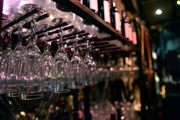 wine glasses stacked on black metal hanging bar glass racks in a bar stock photo