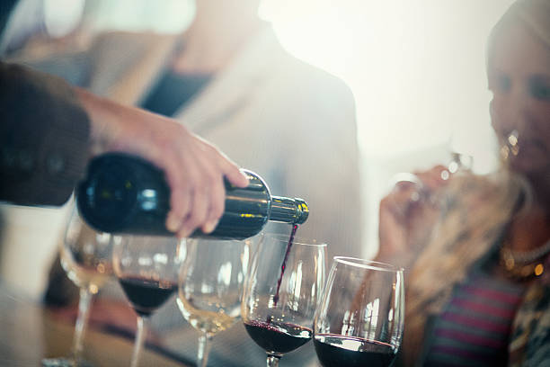 Sekelompok orang dewasa kaukasia yang tidak dapat dikenali mencicipi dan mengevaluasi anggur yang berbeda. Ada beberapa gelas anggur yang diisi dengan anggur yang berbeda. Orang-orang menganalisis penampilan, aroma dan buket, rasa dan tekstur, aftertaste, dan kesan keseluruhan. Backlit, gambar kencang