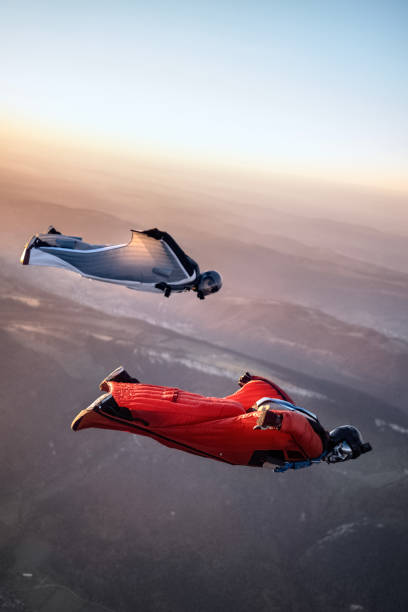 Wingsuit fliers soar above Swiss mountain landscape stock photo