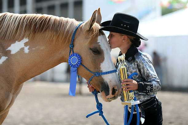 Winning at the County Fair cowgirl contestant holding her ribbons she won with her horse in an arena during fair farmers market photos stock pictures, royalty-free photos & images