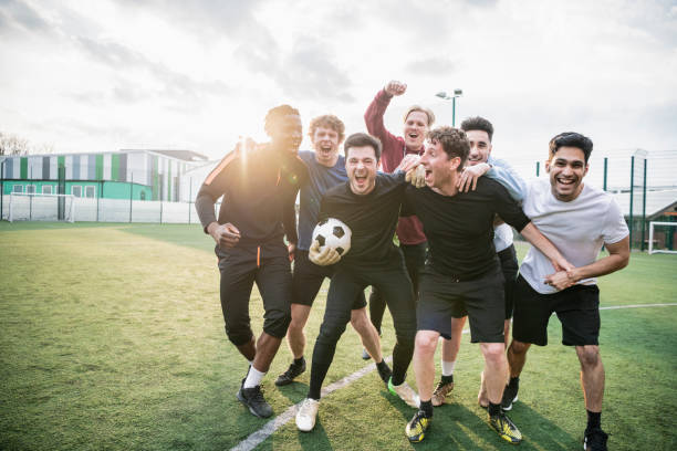 Winning football team cheering Group of young man hugging and celebrating soccer match success equipación fútbol stock pictures, royalty-free photos & images