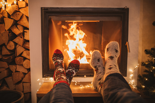 Lazy winter day in front of fire in fireplace. Human legs in Christmas socks in front of fireplace.