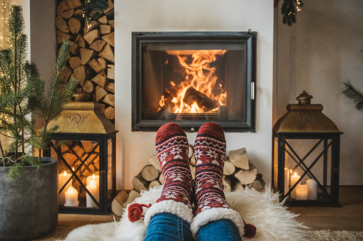 Lazy winter day in front of fire in fireplace. Human legs in socks in front of fireplace.