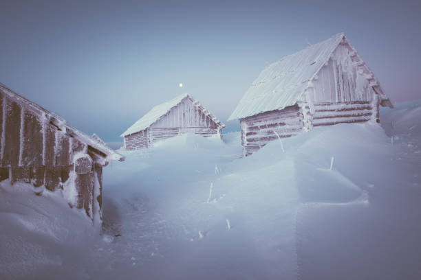 Old wooden house in a mountain village. Morning twilight. Winter...