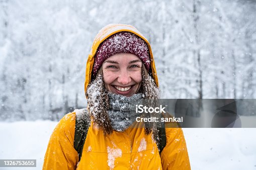 istock Winter portrait of a laughing woman in yellow jacket at blizzard. 1326753655
