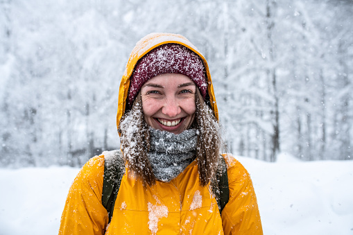 Winter portrait of a laughing woman in yellow jacket at blizzard.