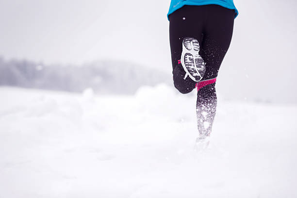Athlete woman is running during winter training outside in cold snow...