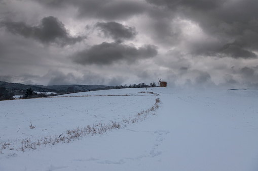 Winter snowy landscape. It is cloudy and there are dramatic gray clouds in the sky.