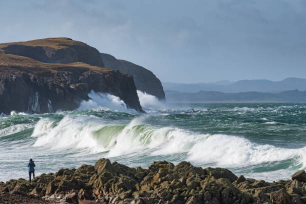 Winter Storm Waves in Dunaff Ireland Photographer taking picture of large waves coming in from the Atlantic ocean on the rocky shore at Dunaff County Donegal Ireland inishowen peninsula stock pictures, royalty-free photos & images