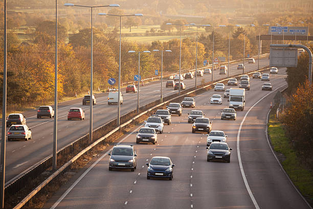 winter sun on sunday motorway traffic essex england - snelweg stockfoto's en -beelden