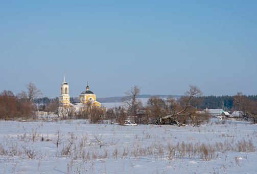 Winter village landscape with Church, the sun shines snow drifts.
