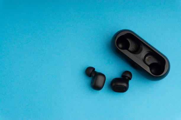 Wireless earbuds or earphones on blue background Wireless earbuds or earphones on blue background bluetooth stock pictures, royalty-free photos & images