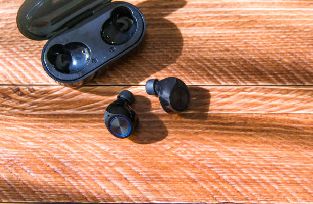 Wireless earphone or headphones with bluetooth connection with its storage and charging box on a wooden table. Copy space stock photo