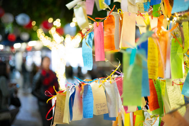 Wishes written on Tanzaku, small pieces of paper, and hung on a Japanese wishing tree, located in the Little Tokyo section of Los Angeles, California, photographed at an outdoor mall at night. stock photo