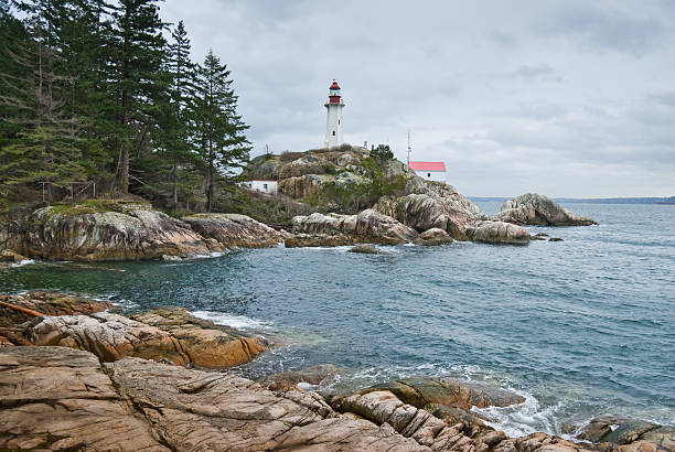 Point Atkinson Lighthouse and Rocky Shore With the advent of radar, GPS and other advanced navigation tools, lighthouses no longer need to perform the same function they once did; guiding ships to safety. Instead they have been preserved as historic monuments; reminding us of a time when shipping and sailing were more perilous activities. The Point Atkinson Lighthouse is located at Lighthouse Park in West Vancouver, British Columbia, Canada. jeff goulden lighthouse stock pictures, royalty-free photos & images