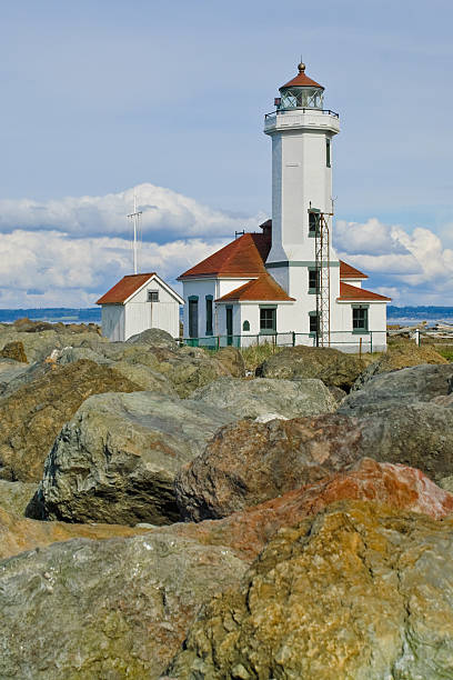 Point Wilson Lighthouse and Rocky Shore With the advent of radar, GPS and other advanced navigation tools, lighthouses no longer need to perform the same function they once did; guiding ships to safety. Instead they have been preserved as historic monuments; reminding us of a time when shipping and sailing were more perilous activities. The Point Wilson Lighthouse is located at Fort Worden State Park near Port Townsend, Washington State, USA. jeff goulden lighthouse stock pictures, royalty-free photos & images