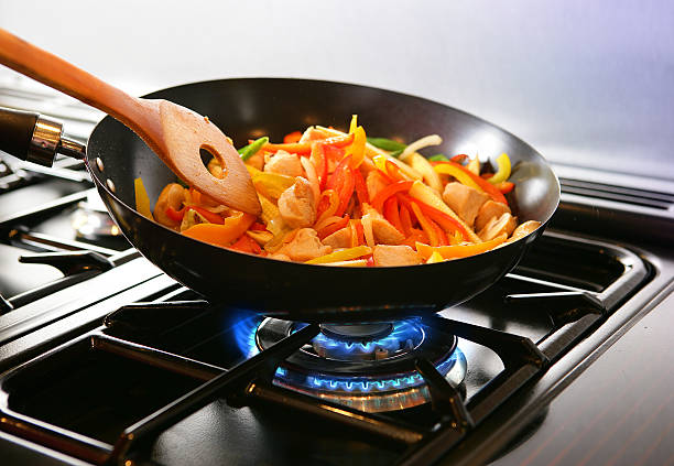 Wok cooking Stirfry Wok cooking Stirfry vegetables and chicken on Gas flame. stove stock pictures, royalty-free photos & images