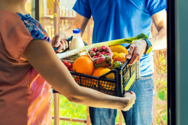 woman accepting groceries box from delivery man at home woman accepting groceries box from delivery man at home home delivery stock pictures, royalty-free photos & images
