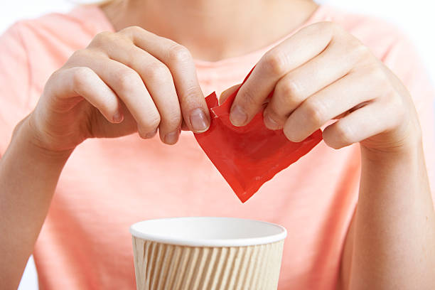 Woman Adding Artificial Sweetener To Coffee stock photo