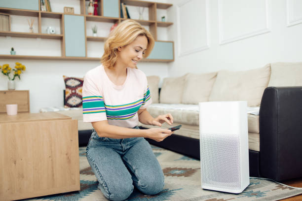 Woman adjusting a home air cleaner using a smart system stock photo