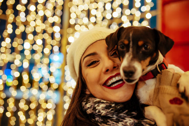 Woman and dog - New Year's Eve Beautiful young brunette woman with Jack Russell terrier enjoying Christmas or New Year night ona a city street. happy new year dog stock pictures, royalty-free photos & images