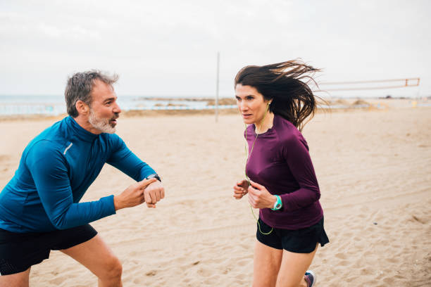 vrouw en haar coach op de strand training - hardlopen vorouw stockfoto's en -beelden