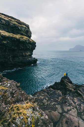 Young Caucasian woman and man   looking at scenic  view from hill on Faroe Islands