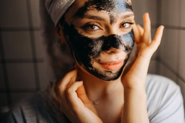 Woman applying black nourishing mask on face stock photo