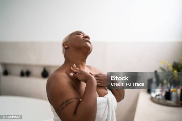 Woman applying body mosture in the bathroom at home
