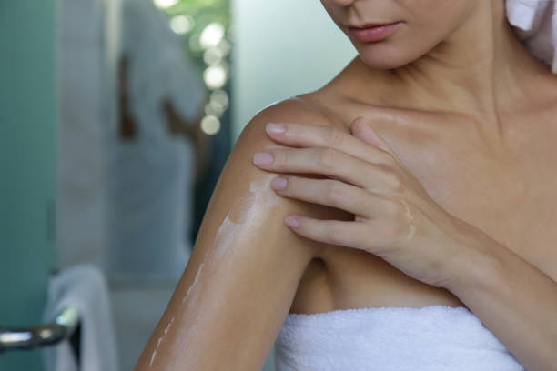 kvinna tillämpa kroppsolja för att återfukta hennes hud efter dusch, skönhet hudvård koncept - smörja in sig bildbanksfoton och bilder